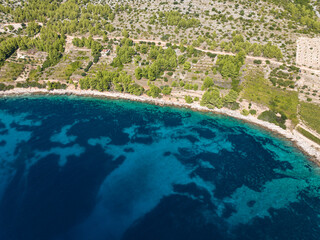 AERIAL: Stunning turquoise sea reaches rocky shoreline of Mediterranean island