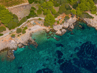 AERIAL: Flying above a beach with rocky cliffs descending into the turquoise sea