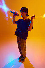 Young man, microphone in hand, captivates the audience with a soulful rap performance, weaving rhymes and emotions against yellow background in neon light. Concept of music, performance, live concert