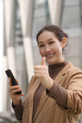 Confident Businesswoman Giving Thumbs Up with Smartphone