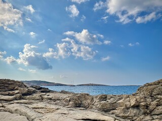 seascape of Malta from a rocky coast of St Paul's Bay on a summer day with a view of a sailboat on...