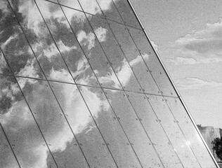 Clouds reflection on a glass wall of a business center, black and white photo background. Pencil sketch drawing illustration