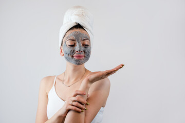 Beautiful girl with mud oy black clay facial mask isolated on white