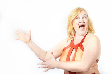 Funny cute mature adult woman with blonde hair in a swimsuit on a white background. Fat middle-aged lady poses in underwear in studio. The concept of body positivity