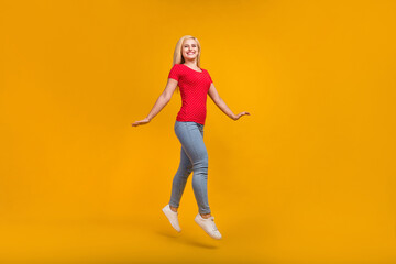 Fototapeta na wymiar Full length body size photo woman jumping up smiling isolated vivid orange color background