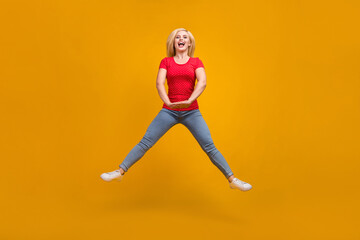 Full length body size photo woman jumping up playful isolated vibrant orange color background