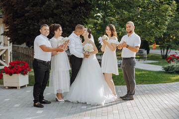 A group of people are posing for a picture, with a bride and groom in the center. The bride is...