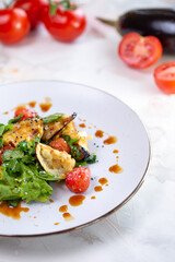 Fresh salad with grilled vegetables, greens, and tomatoes on a white plate