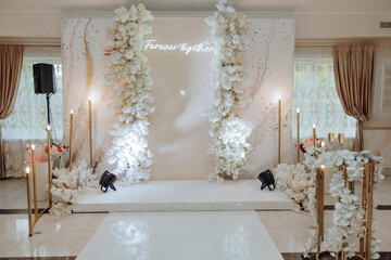 A white and gold wedding reception hall with a white archway and a sign that says Forever Together