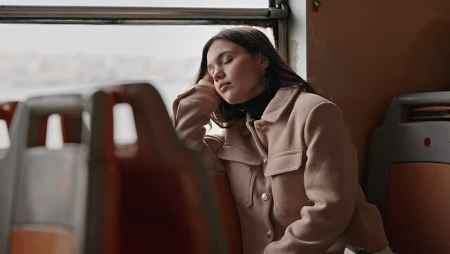 A young woman is seen sleeping peacefully in a ferry seat during her early morning commute, suggesting a busy lifestyle and the need for rest.