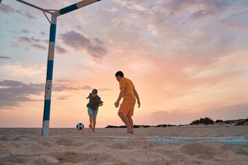 Father and Son playing football, family fun outdoors players in soccer in dynamic action have fun...