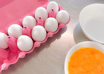 White chicken eggs in a pink egg tray. Fresh organic chicken eggs in an open carton or egg container, set 10 of 12, stock photo in the kitchen.