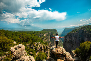Man opens his arms and watches the fascinating nature view. The magnificence and majestic cliffs of...