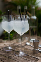 White cocktail with ice in a glass with a stem on a wooden surface