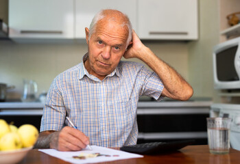 Man sitting at table at home calculating domestic finances and bills - 800250978