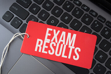 Exam results word written on red paper note on computer keyboard.