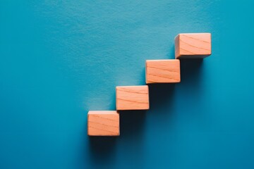 Wooden blocks in stair like formation speak to growth and progress against blue backdrop