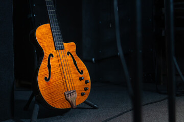 Close-up of a beautiful electronic guitar stands on the floor in the studio, illuminated by light...