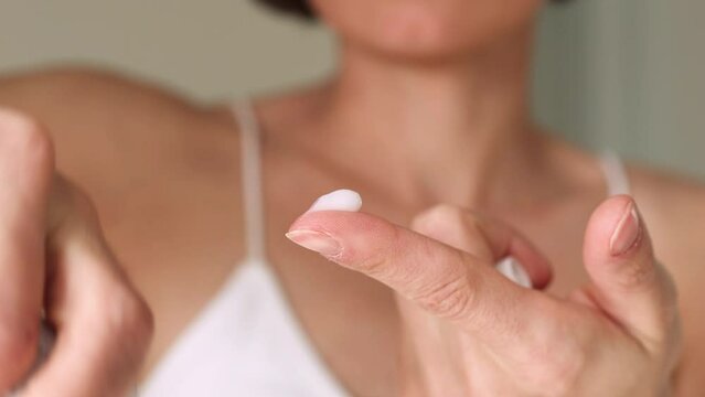 A woman presses the ointment onto her finger and applies it to the bite site by a bedbug on her shoulder on a white background, close-up. Skin health problem. Red pimples.