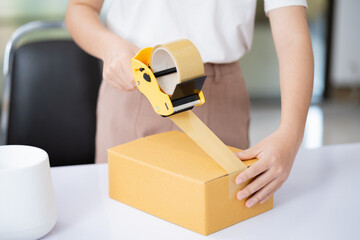 Female post mail storage worker holding tape dispenser sealing shipping online store order courier...