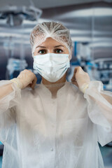  beautiful nurse wear uniform gloves mask and medical hairnet standing  at surgery room at hospital