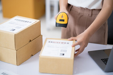 Young business online woman scanning package label with barcode reader at storehouse.
