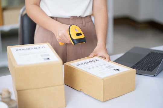 Young business online woman scanning package label with barcode reader at storehouse.