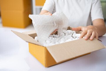 Small business entrepreneur woman packing product in mailing box for shipping from online store....