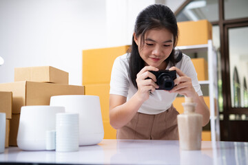 Young Asian business entrepreneur using a compact digital camera take a photo of product for upload...