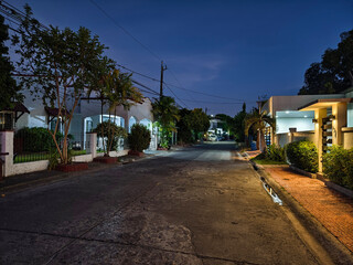 Las Pinas, Metro Manila, Philippines - Evening scene on a typical suburban street in BF Resort Village with houses and parked cars under a vibrant sunset sky.