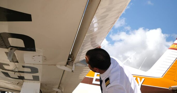 A close up shot of a pilot under the wing of his plane checking the flap