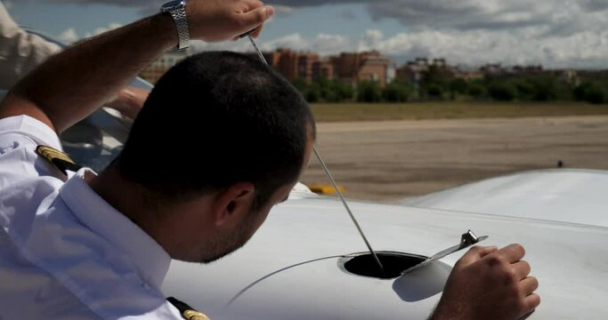A pilot checking the engine oil level with the dipstick