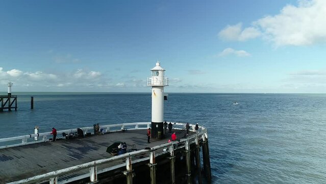 Drone footage of the lighthouse on a fishing pier at sunset in Blankenberge, Belgium