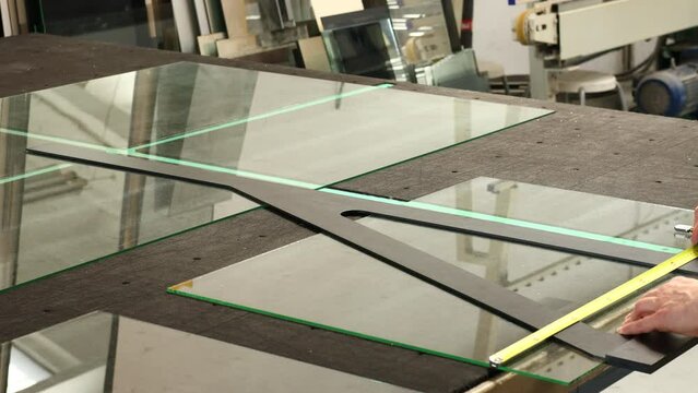 A professional glazier cuts glass by hand, glass factory