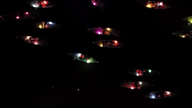 Drone top-down view on illuminated boats sailing on the river of Hoi An in Vietnam at night