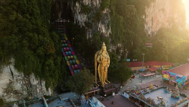 Aerial footage of the Batu Caves Hindu temple in Malaysia, showcasing a golden statue of Buddha.