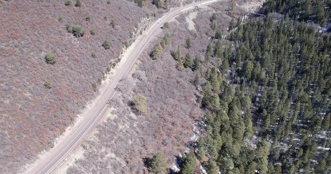 Top down view of a rural mountain highway flies to a historic truss bridge with narrow gauge railway near Cloudroft, New Mexico