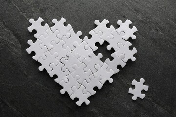 Obraz premium Heart made of puzzles with missing piece on black table