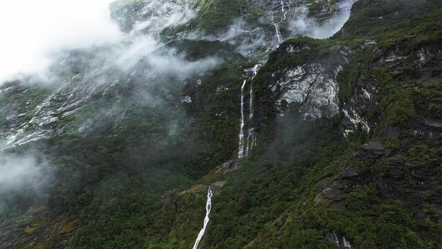 Aerial panoramic parallax upward angle of waterfall cascading between clouds