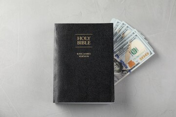 Holy Bible and money on grey table, top view