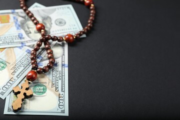 Dollars and prayer beads on grey table, space for text