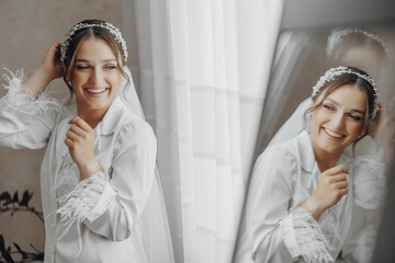 A woman is wearing a white dress and a white veil. She is smiling and looking at the camera