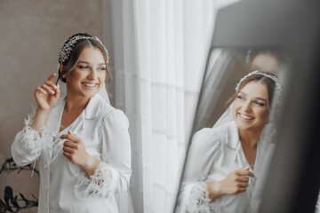 Naklejka premium A woman is wearing a white dress and a headband. She is smiling and looking at herself in a mirror