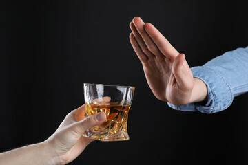 Alcohol addiction. Man refusing glass of whiskey on dark background, closeup