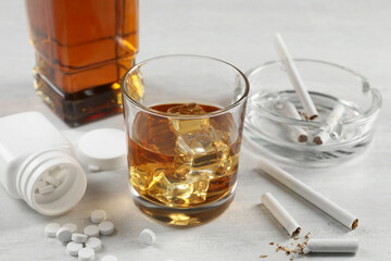 Alcohol and drug addiction. Whiskey in glass, cigarettes and pills on white table