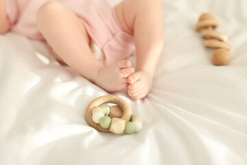 Cute baby and rattle toys on sheets, closeup