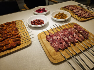 skewers with raw meat on wooden plate
