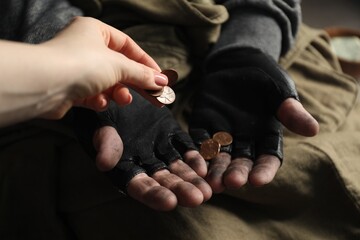 Woman giving coins to poor homeless man, closeup. Charity and donation