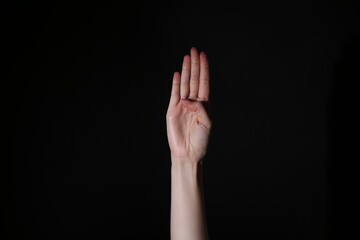 Woman showing open palm on black background, closeup