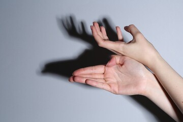 Shadow puppet. Woman making hand gesture like deer on grey background, closeup